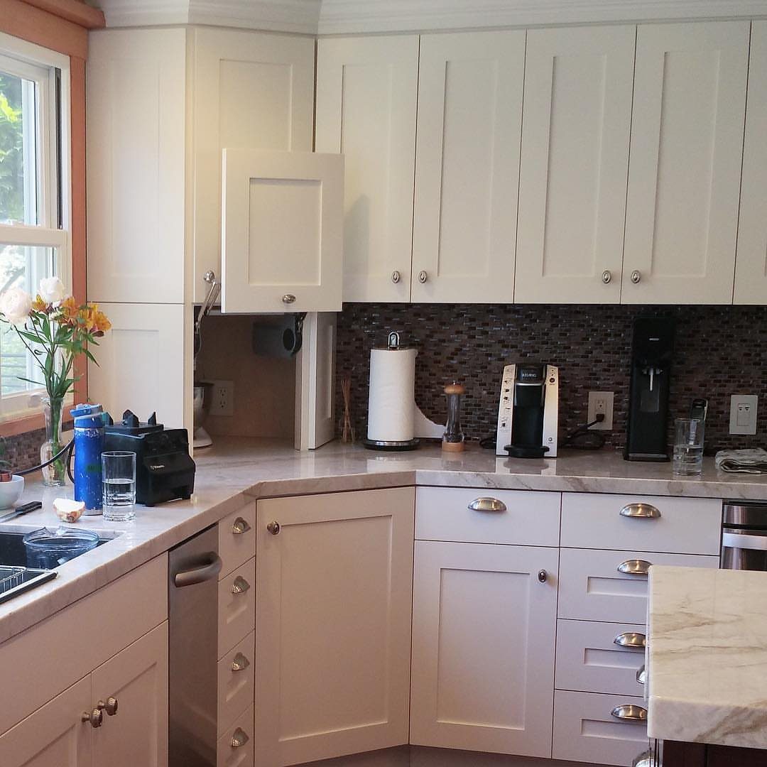 White kitchen cabinets with an open appliance garage revealing coffee makers and kitchen tools.