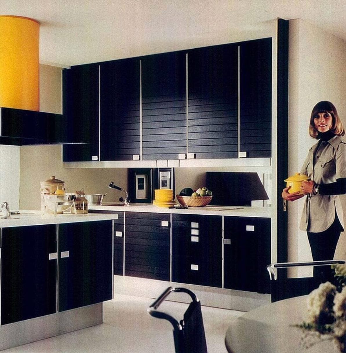 Black kitchen cabinets with silver hardware and white countertops in a retro-style kitchen setting.