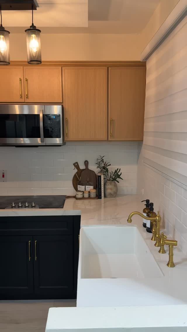 Black lower kitchen cabinets paired with light wood upper cabinets and a white farmhouse sink.