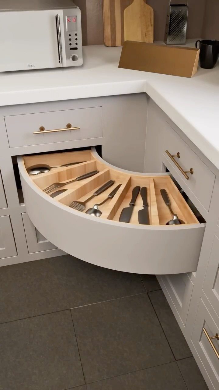 A curved corner kitchen drawer pulled open showing organized cutlery in wooden dividers.