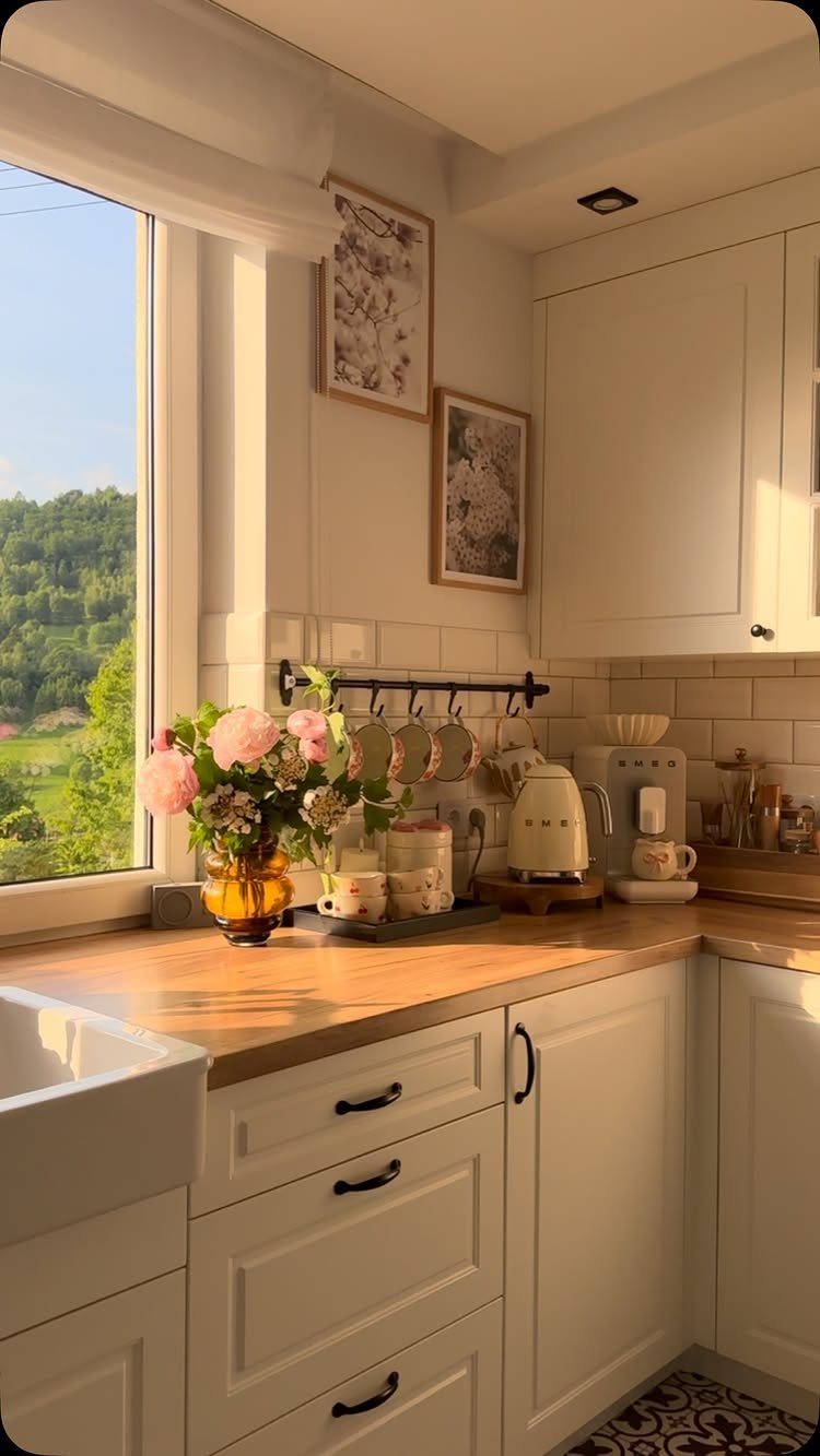 Pink flowers in a yellow vase and a tray with a kettle on a wooden countertop.