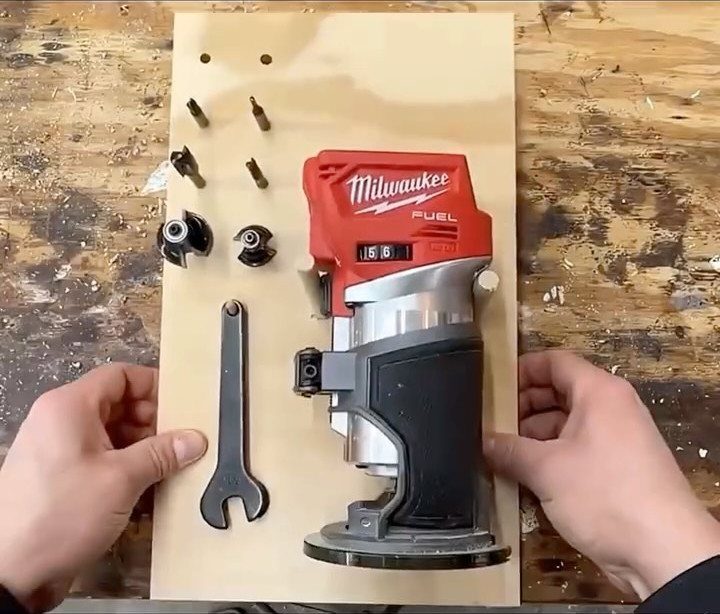 A red Milwaukee router and various metal tools laid out on a wooden board.