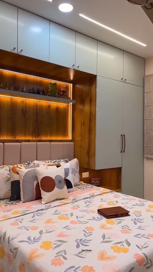 Built-in light blue and wood bedroom wardrobe with integrated warm lighting above a bed.