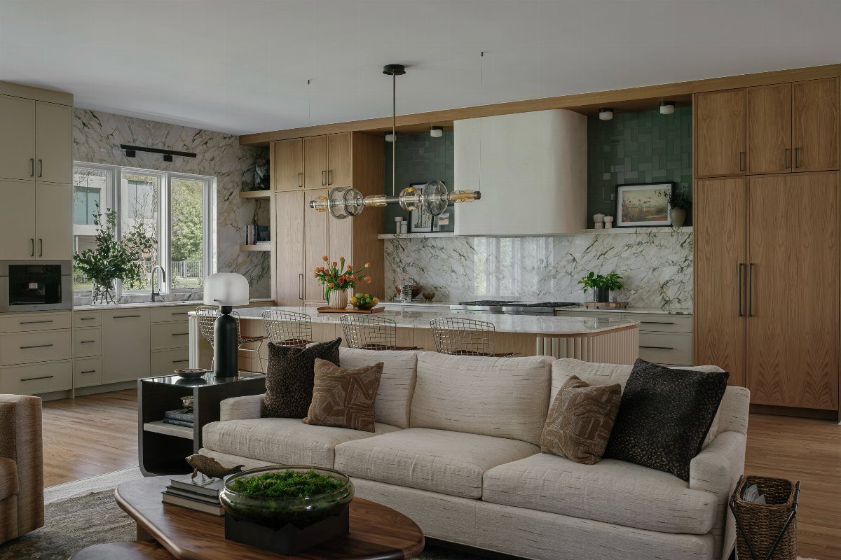 A modern open concept living room and kitchen with a large sofa and wooden cabinetry.