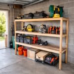 Wooden three-tier shelves holding various power tools and storage bins in a garage setting.