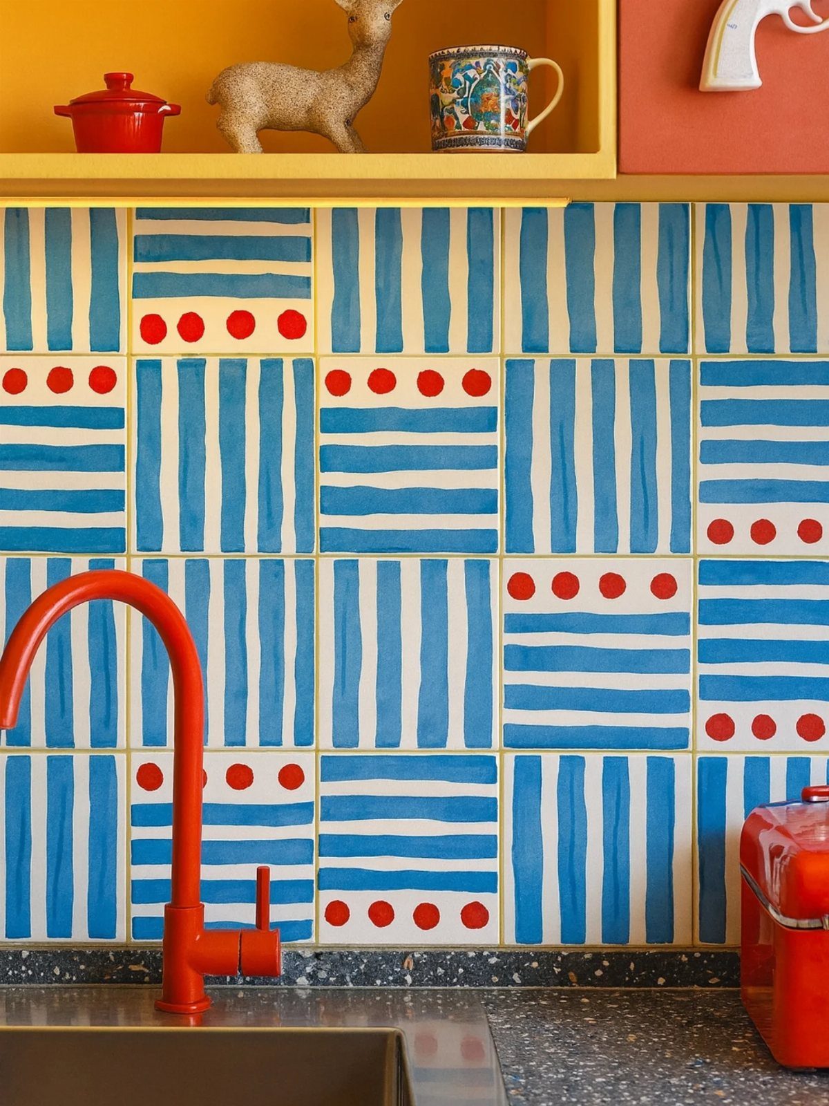 Hand-painted blue and white striped tiles with red polka dots forming a kitchen backsplash.