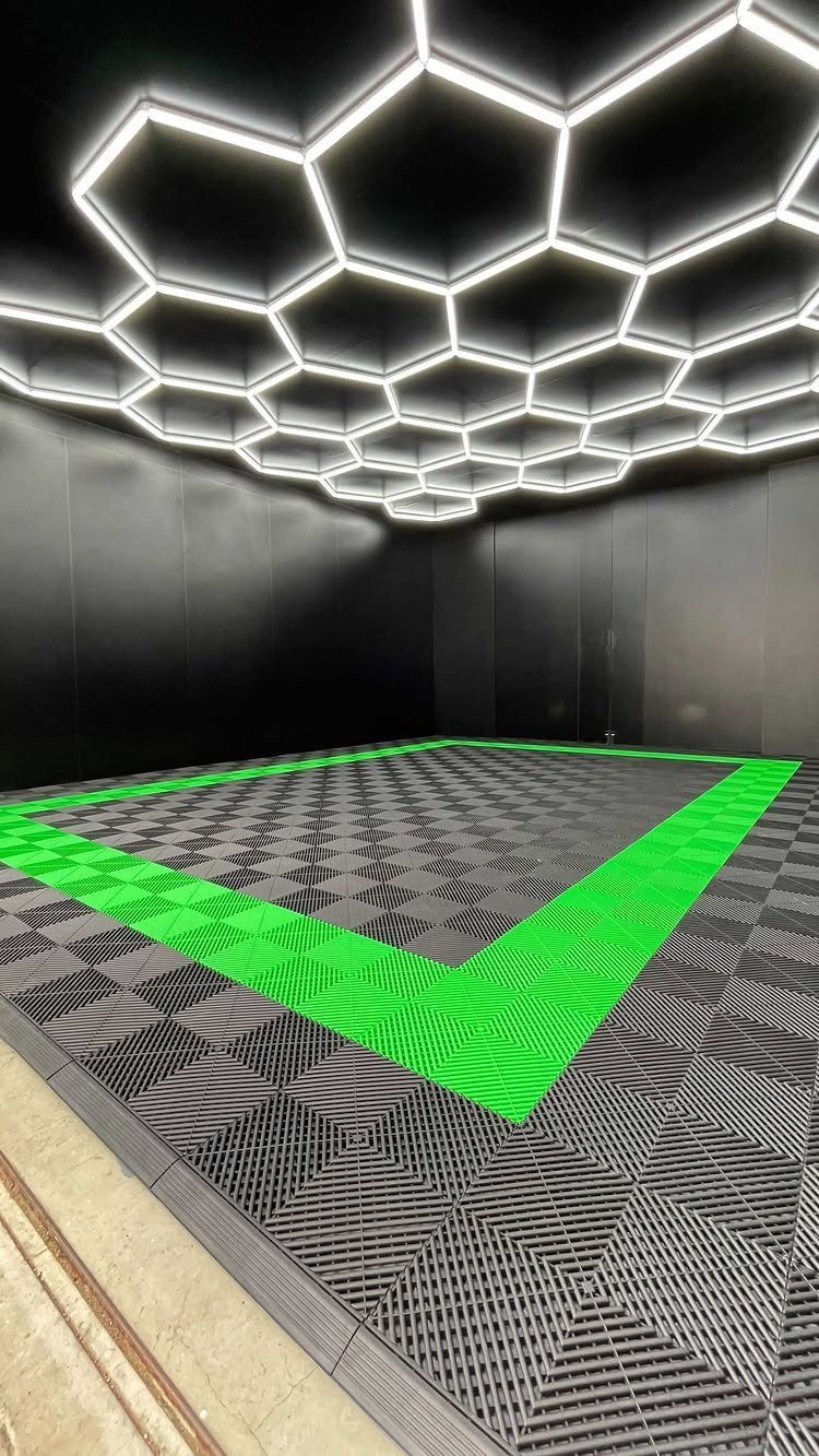 Hexagonal LED lights hang above a grey and green modular tiled garage floor.