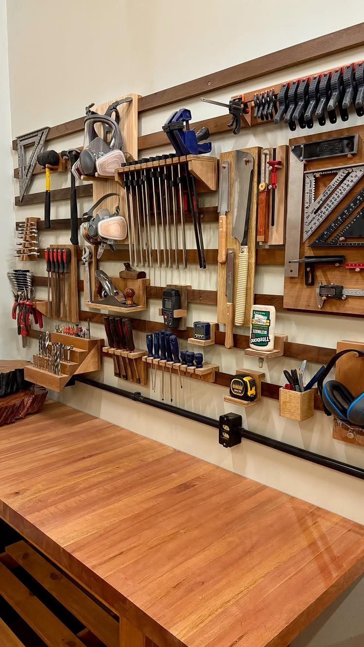 Various hand tools and clamps organized on a wooden wall-mounted storage system above a workbench.