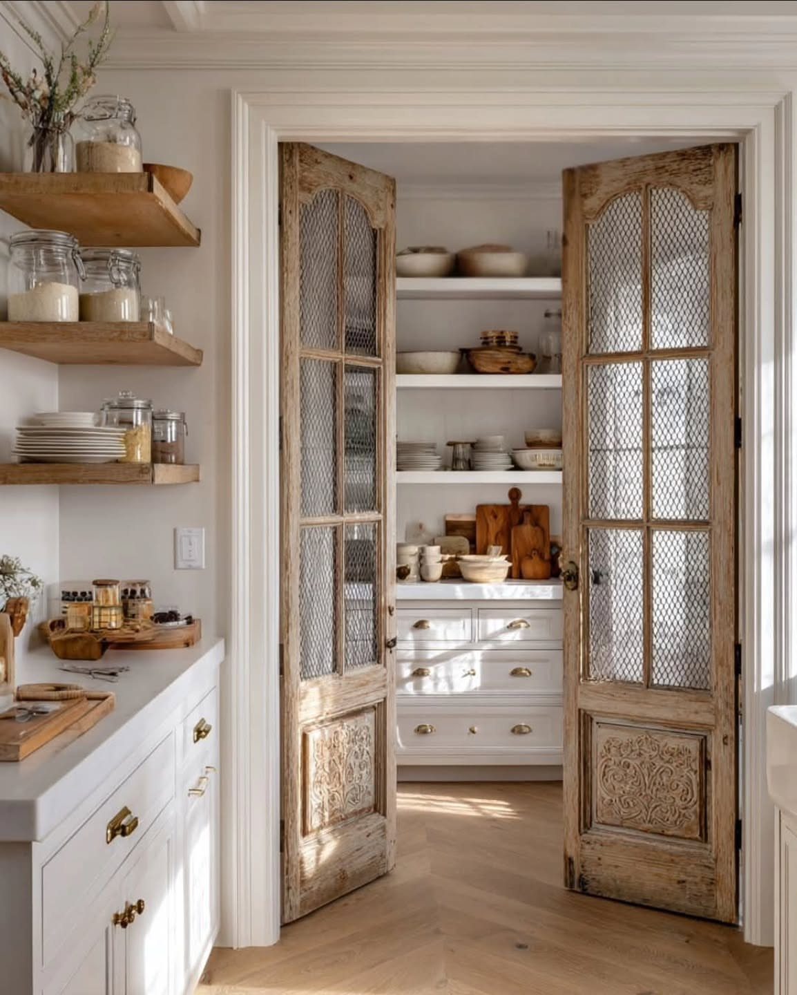 Vintage wooden French doors with mesh inserts opening into a bright, organized kitchen pantry.